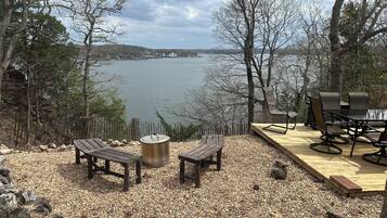 Une terrasse dotée de mobilier d’extérieur, offrant une vue sur un lac et entourée d’arbres.