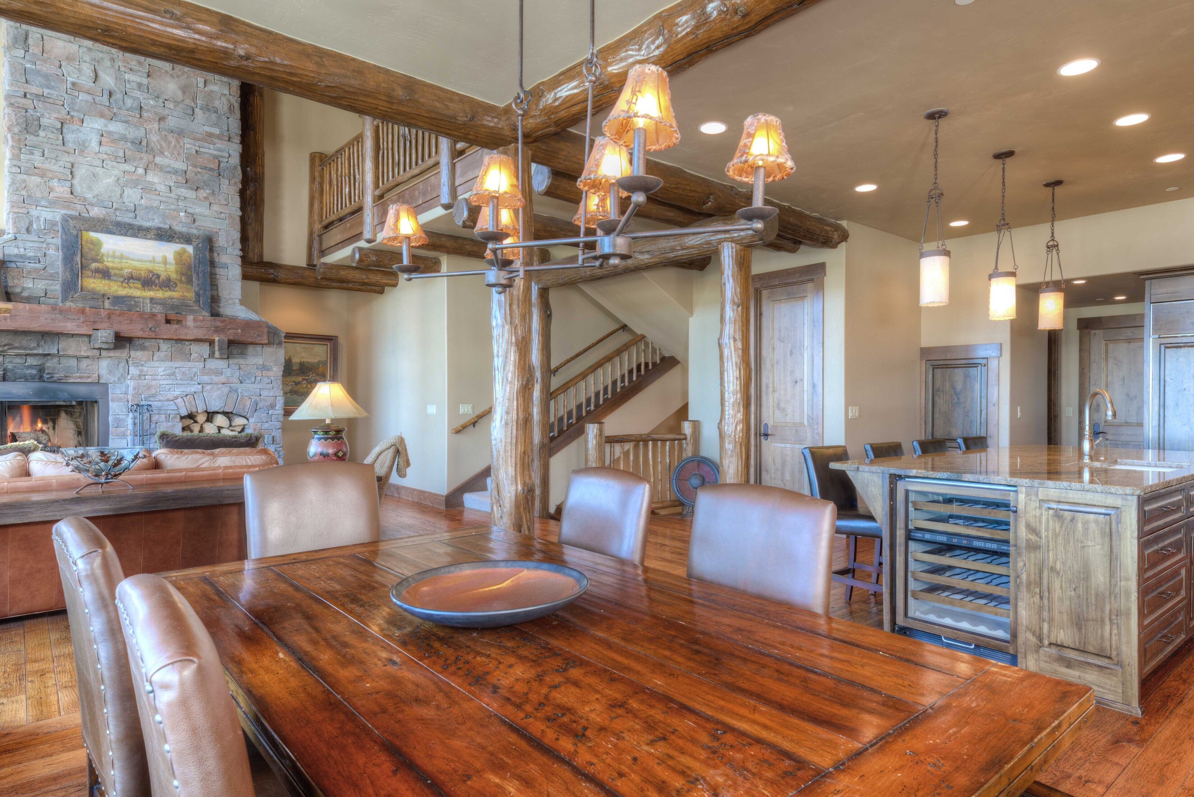 A spacious dining area with a large wooden table, leather chairs, and a stone fireplace.