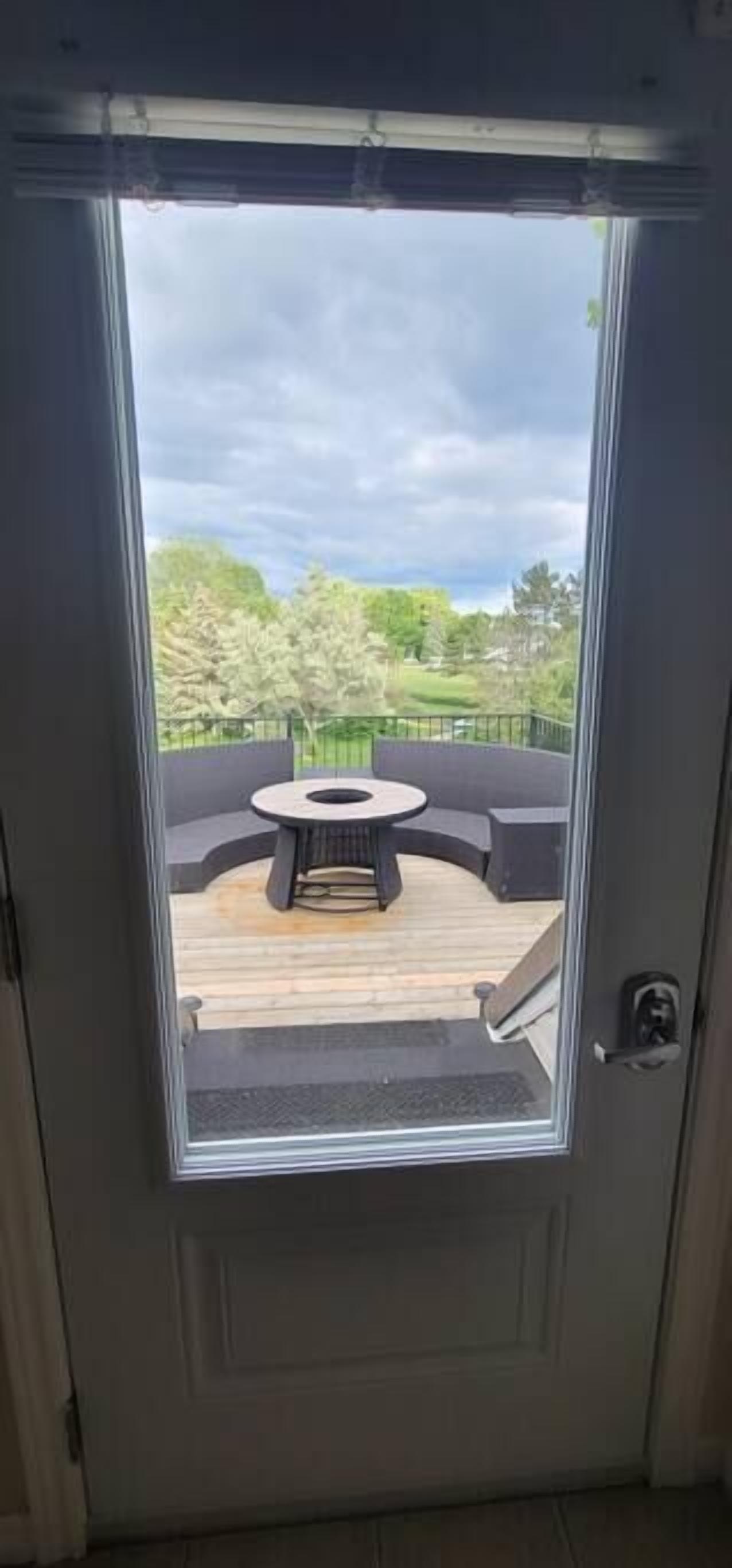 Une porte donnant sur une terrasse extérieure avec une table ronde et des sièges.
