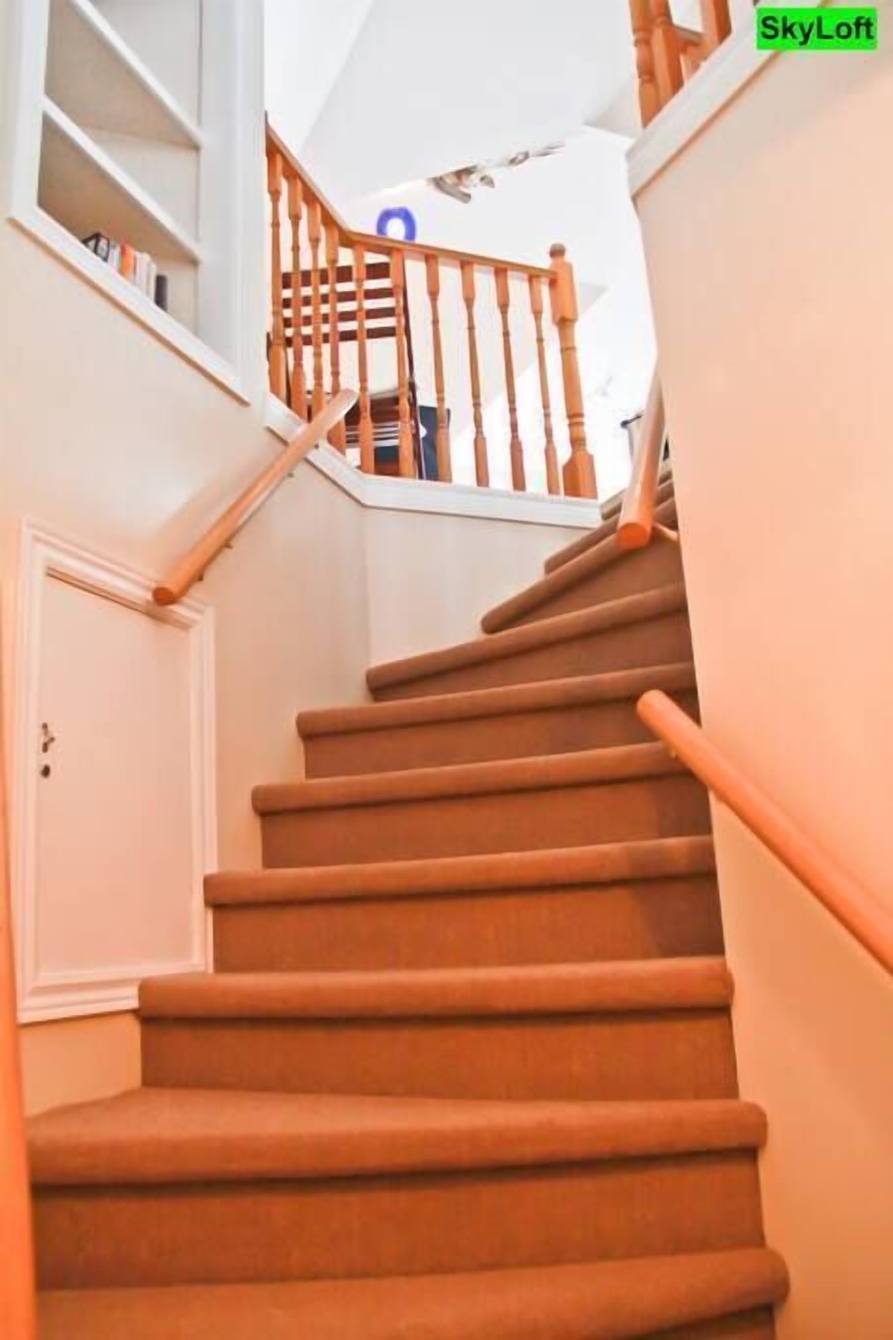 Un escalier avec des rampes en bois et une porte blanche en bas.