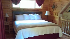 A wooden cabin bedroom with a bed, two bedside lamps, and a window with curtains. - Private Mountain Hideaway (Andrews)
