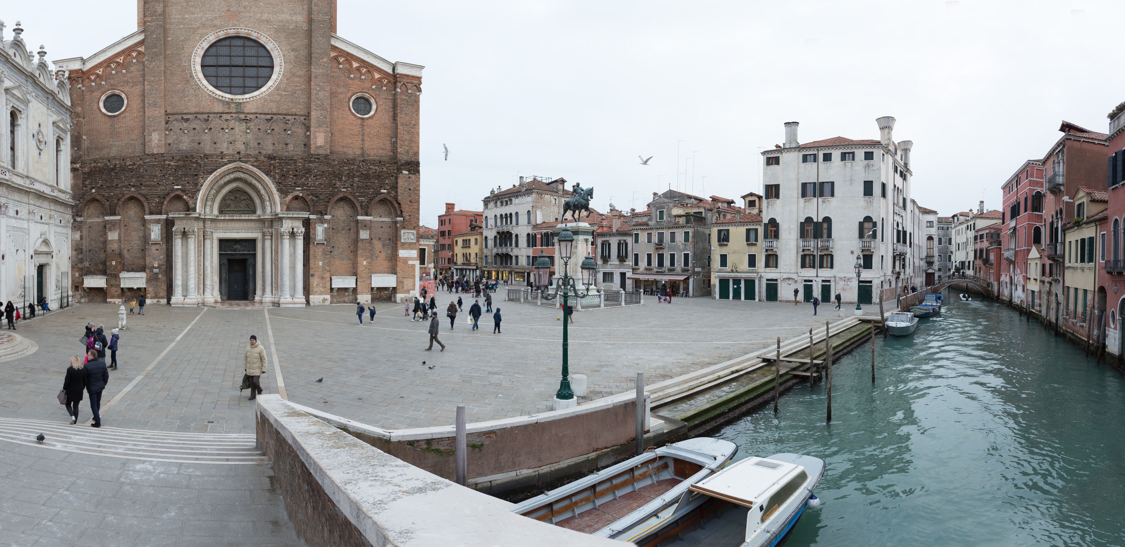 A historic square with a prominent church, a canal with boats, and traditional buildings.