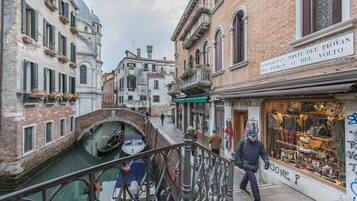 Un estrecho canal veneciano con una góndola, edificios con arquitectura tradicional veneciana y una tienda con un letrero en italiano.