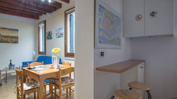Un área de comedor con una mesa y sillas de madera, un mapa en la pared y un letrero de zona Wi-Fi.