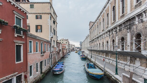 Um canal estreito ladeado por edifícios históricos com barcos atracados.