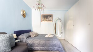 Quarto com cama, sofá, espelho, lustre e um quadro na parede.