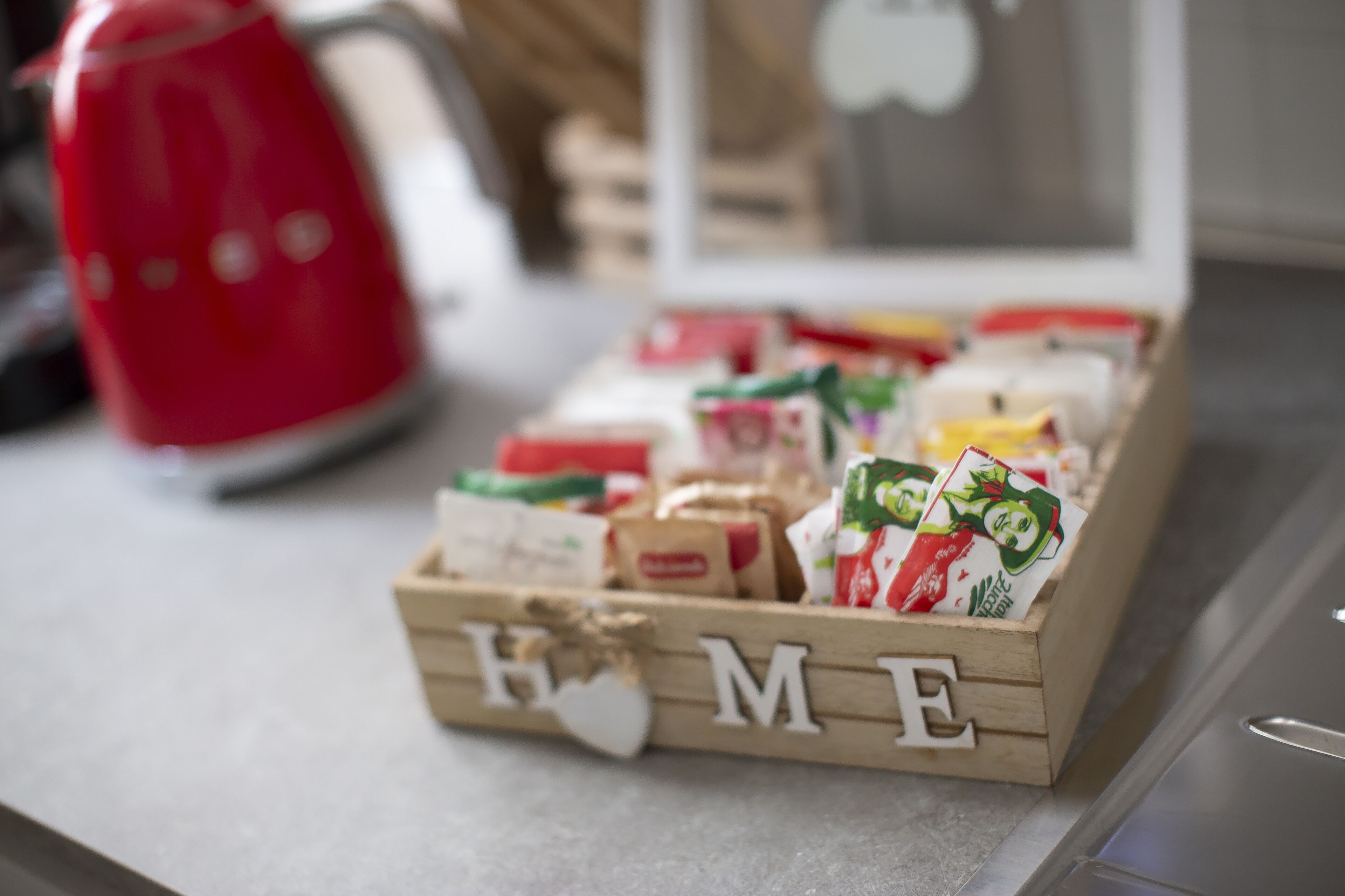 A wooden box with the word "HOME" on it, containing various packaged food items.