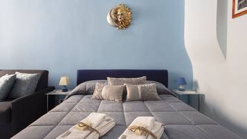 Una cama bien hecha con almohadas, una lámpara de noche y un adorno de pared.
