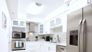 Una cocina moderna con armarios blancos, electrodomésticos de acero inoxidable y un salpicadero de azulejos.