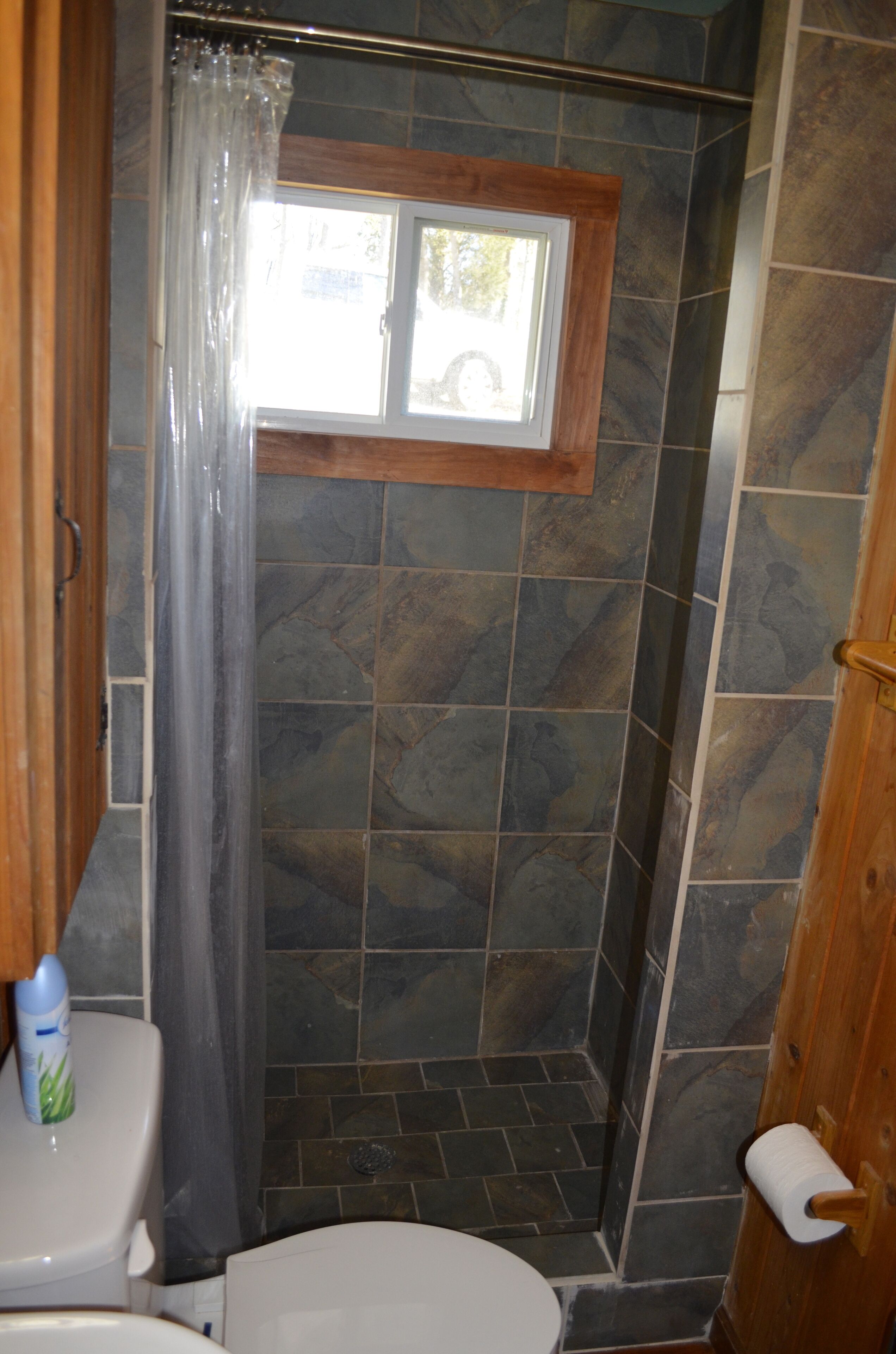 Une salle de bain avec une douche, des toilettes et une fenêtre.
