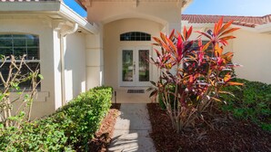 A house with a tiled roof, a front door with glass panels, and a small pathway leading to the entrance. - Near Disney and USTA tennis campus - Pool Villa on the Lake - Stunning Views! (Kissimmee)
