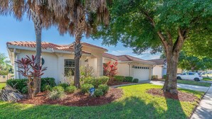A residential property with a tiled roof, a well-maintained lawn, and mature trees. - Near Disney and USTA tennis campus - Pool Villa on the Lake - Stunning Views! (Kissimmee)