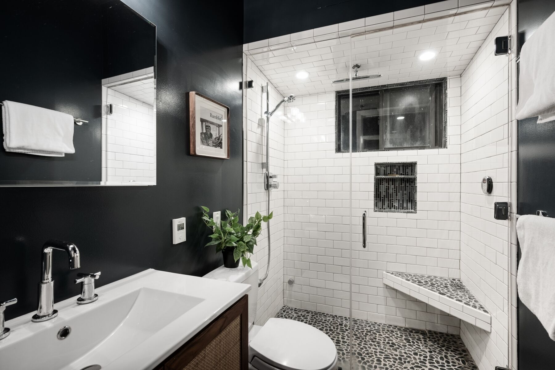 A modern bathroom with a white sink, a toilet, and a shower area.