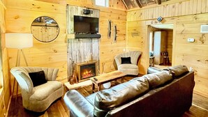 Ein gemütliches Blockhaus-Interieur mit Kamin, Ledersofa und Holzwänden.