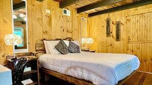 Ein Zimmer mit Holzboden, einem Bett, zwei Nachttischen, einem Stuhl und einem Schreibtisch.
