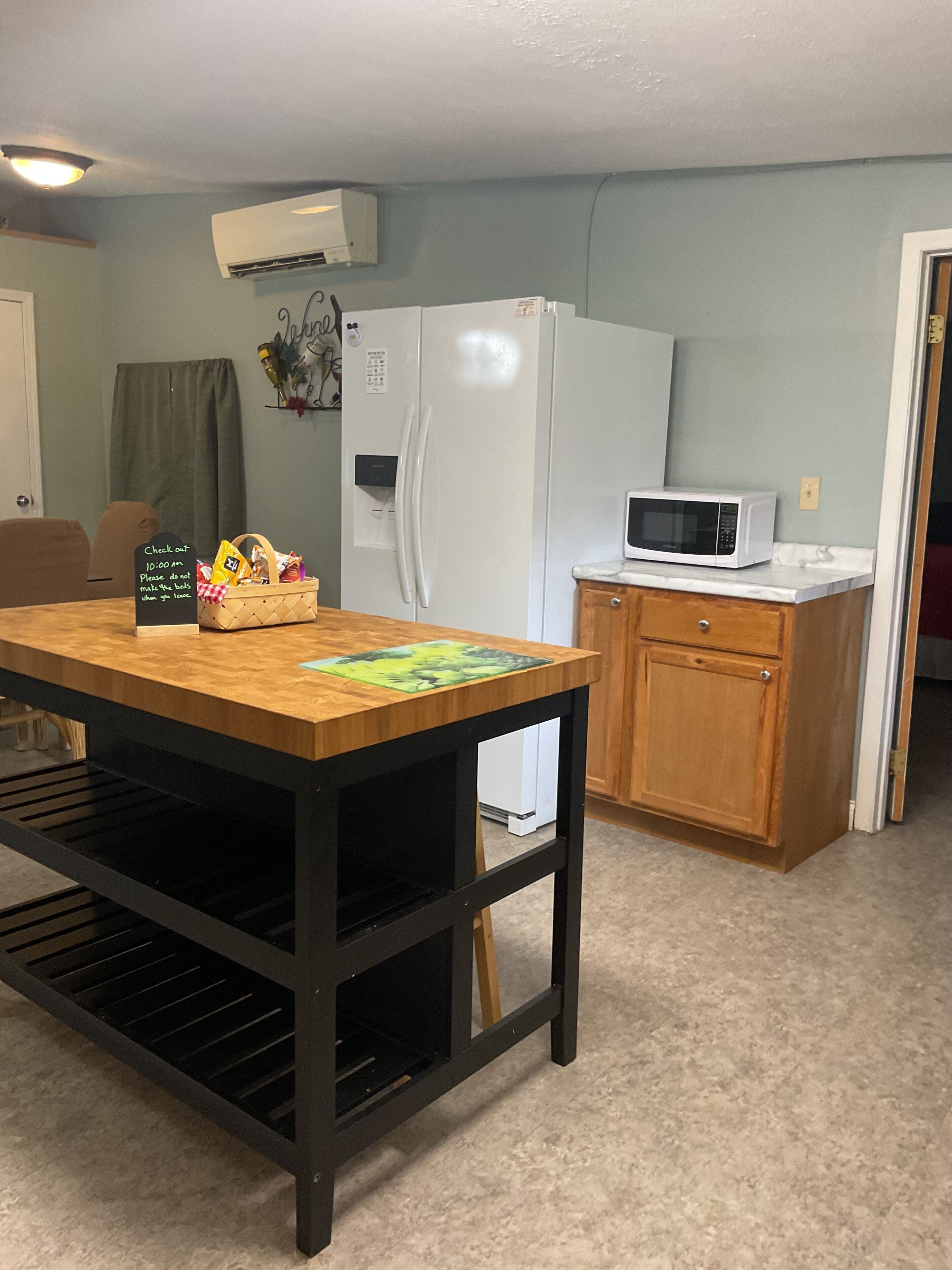 A kitchen with a wooden table, a white refrigerator, a microwave, and a cabinet.