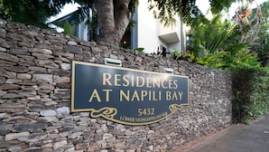 A stone wall with a sign for 'Residences at Napili Bay' at 5432 Lower Honoapiilani Rd.
