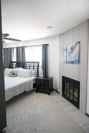 A bedroom with a bed, bedside table, and a fireplace.