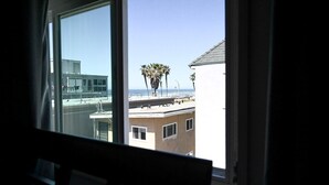 A view from a window overlooking a beach with palm trees and buildings. - Amazing Proximity to the Beach and Bay with Direct Ocean Views! (San Diego)