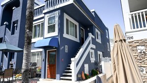 A two-story building with a blue exterior, white trim, and a staircase leading to the second floor. - Amazing Proximity to the Beach and Bay with Direct Ocean Views! (San Diego)