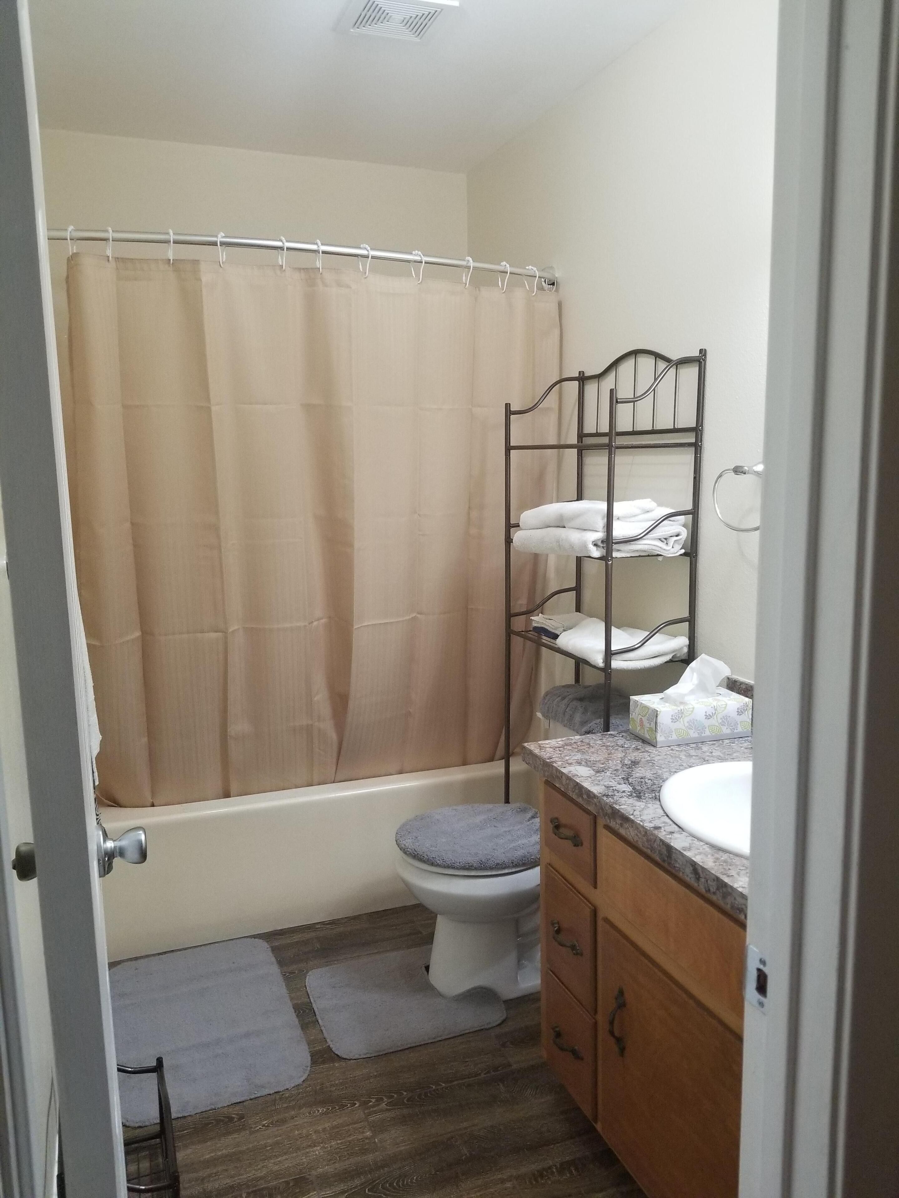 Une salle de bain équipée d’un rideau de douche, de toilettes, d’un lavabo et d’un porte-serviettes.