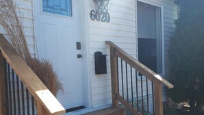 A house with a white exterior, a front door with a blue window, and a wooden staircase leading to the entrance. - Entire house 10 minute walk to The Falls and all Attractions! No Car Needed (Niagara Falls)