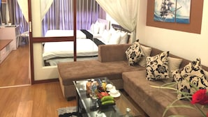 Une chambre d’hôtel avec un lit, un canapé, une table basse en verre et un tableau au mur.