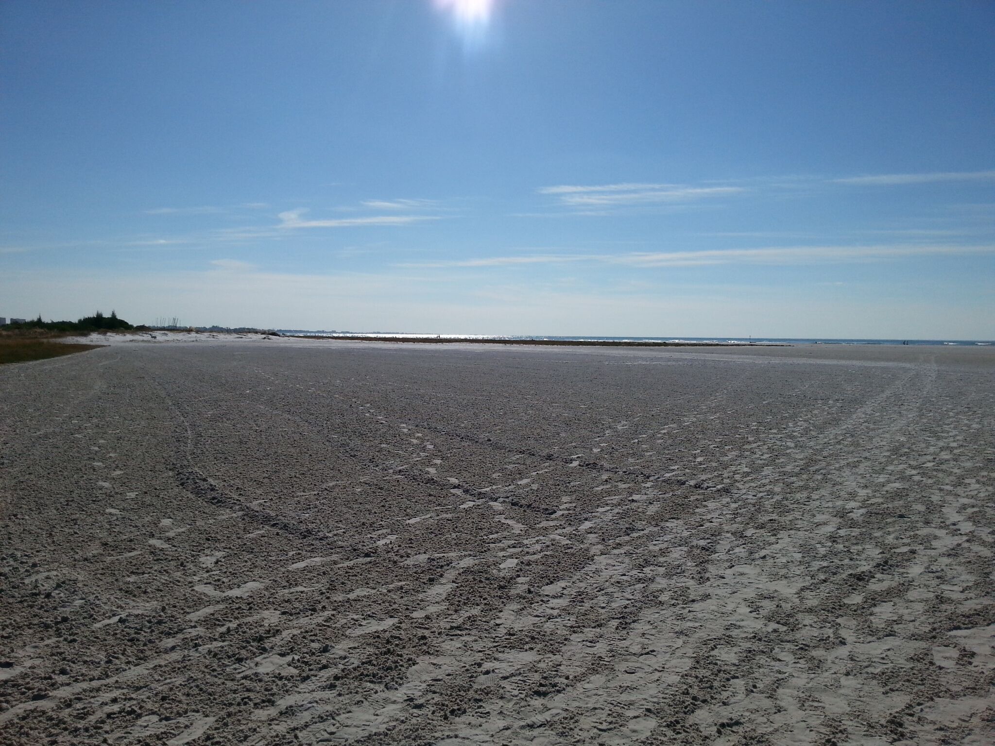 A wide, open beach with a clear sky and distant horizon.