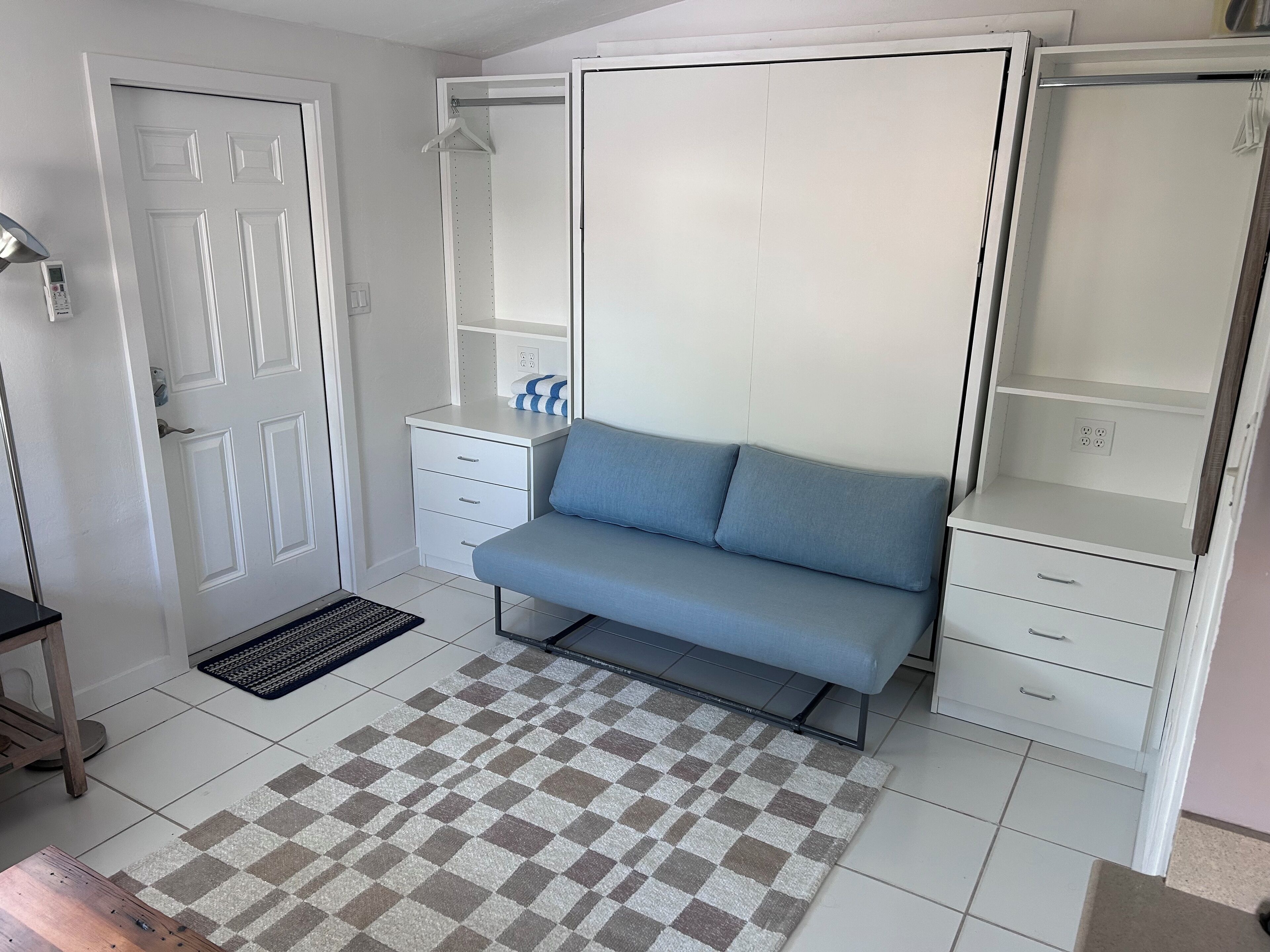 A bedroom with a bed, a wardrobe, a desk, and a chair.