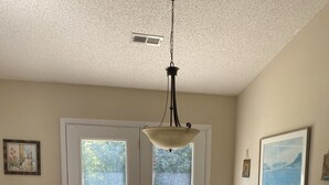 A dining area with a wooden table, four chairs, and a hanging light fixture. - Family & Pet-Friendly,  Near Beaches + Restaurants,  2BR, 2BA (Wilmington)