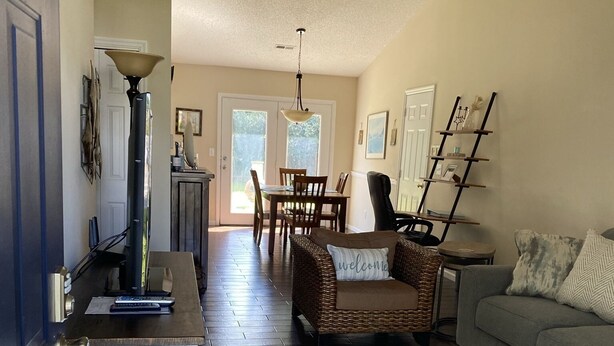 A spacious living area with a dining table and chairs, a sofa, and a kitchen area with a countertop and cabinets. - Family & Pet-Friendly,  Near Beaches + Restaurants,  2BR, 2BA (Wilmington)