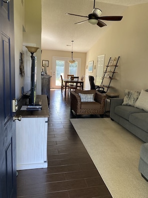 A spacious living area with a dining table and chairs, a sofa, and a kitchen area with a countertop and cabinets.