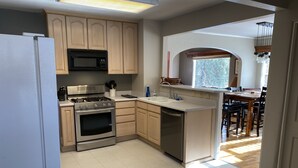 A modern kitchen with stainless steel appliances, wooden cabinets, and a large window providing natural light. - Great Location in Cheyenne Cañyon, 3Bd, 1.5Bath, Private fenced yard and deck! (Colorado Springs)