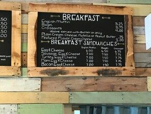 A menu board with breakfast and sandwich options, prices, and a small section for juice.