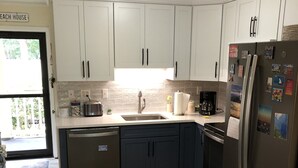 A modern kitchen with white cabinets, a stainless steel refrigerator, and a wooden floor. - WALK TO THE BEACH!!  First floor condo, fully renovated (Hilton Head Island)