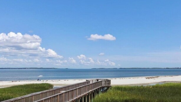 A wooden boardwalk leading to a sandy beach with a clear blue sky and distant land. - WALK TO THE BEACH!!  First floor condo, fully renovated (Hilton Head Island)