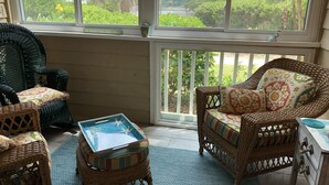 A sunroom with wicker furniture, a glass coffee table, and a view of a lush garden. - WALK TO THE BEACH!!  First floor condo, fully renovated (Hilton Head Island)