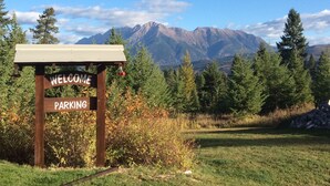 Un panneau en bois sur lequel est écrit « PARCING », avec en arrière-plan un paysage de montagnes et d’arbres.
