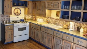 A kitchen with wooden cabinets, a stove, and a sink. - Casa Madre 3 bedroom/2 baths (Taos)