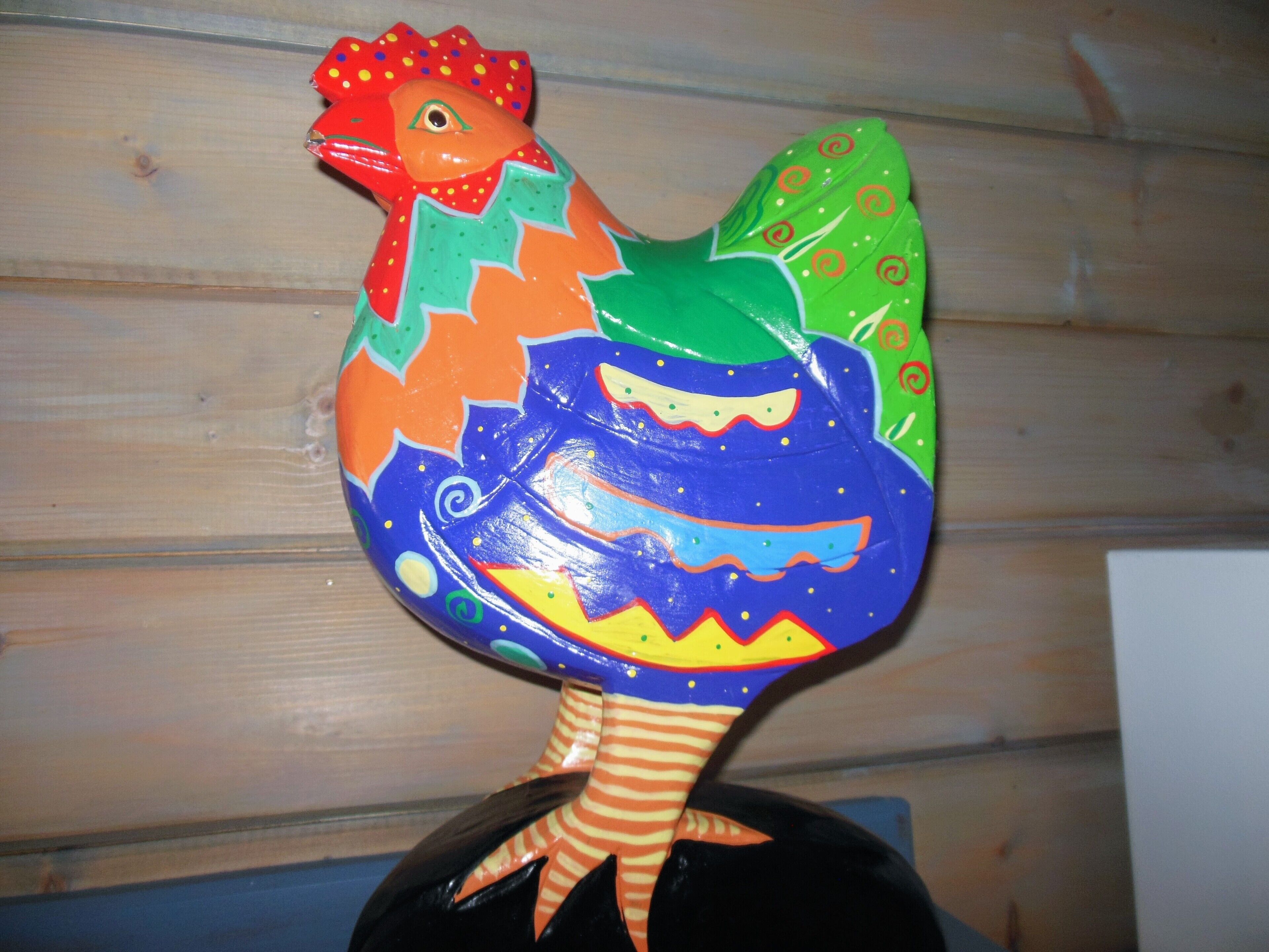 En farverig skulptur af en hane med en stribet fod.