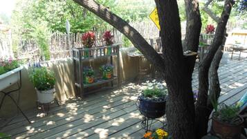 A wooden deck with potted plants and a metal barbecue grill.