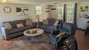 Un salon avec un canapé, un fauteuil, une table basse et une horloge au mur.
