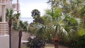 Un hôtel avec vue sur la mer, des palmiers et un immeuble doté de balcons.