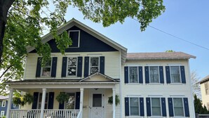 A two-story house with a porch, a front door, and a mailbox. - Trackside Home- Walk to Everything (Track, Town, SPAC) (Saratoga Springs)