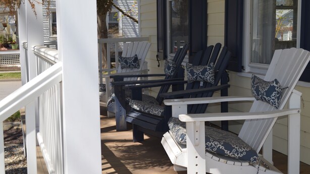 A porch with two Adirondack chairs, one white and one black, with patterned cushions. - Trackside Home- Walk to Everything (Track, Town, SPAC) (Saratoga Springs)