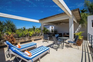 A covered outdoor area with lounge chairs, a table, and chairs.
