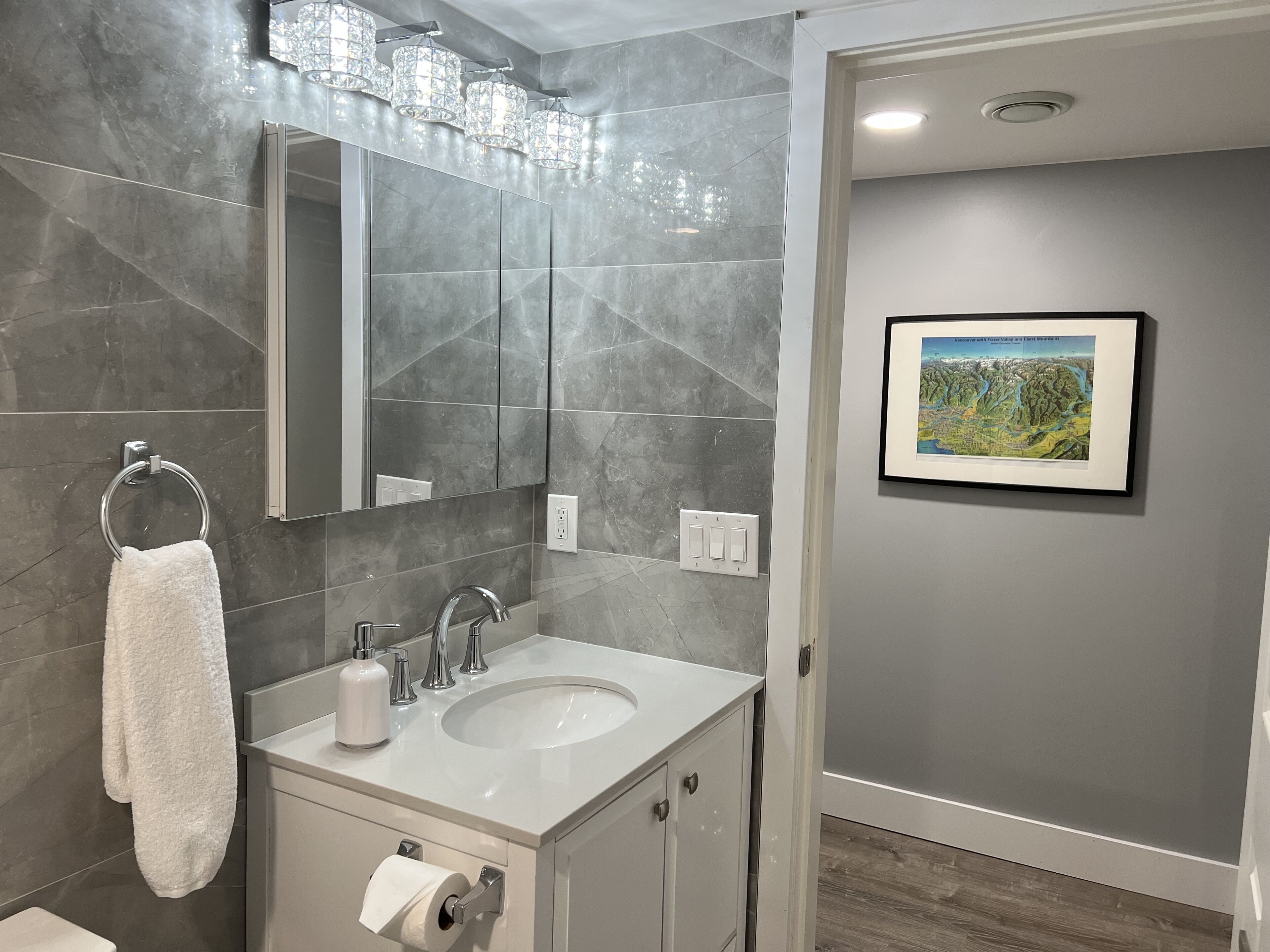 Un baño moderno con un espejo grande, un lavamanos y un inodoro.