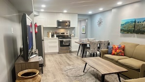 A compact living space with a kitchenette, a sofa, a dining table, and a TV.