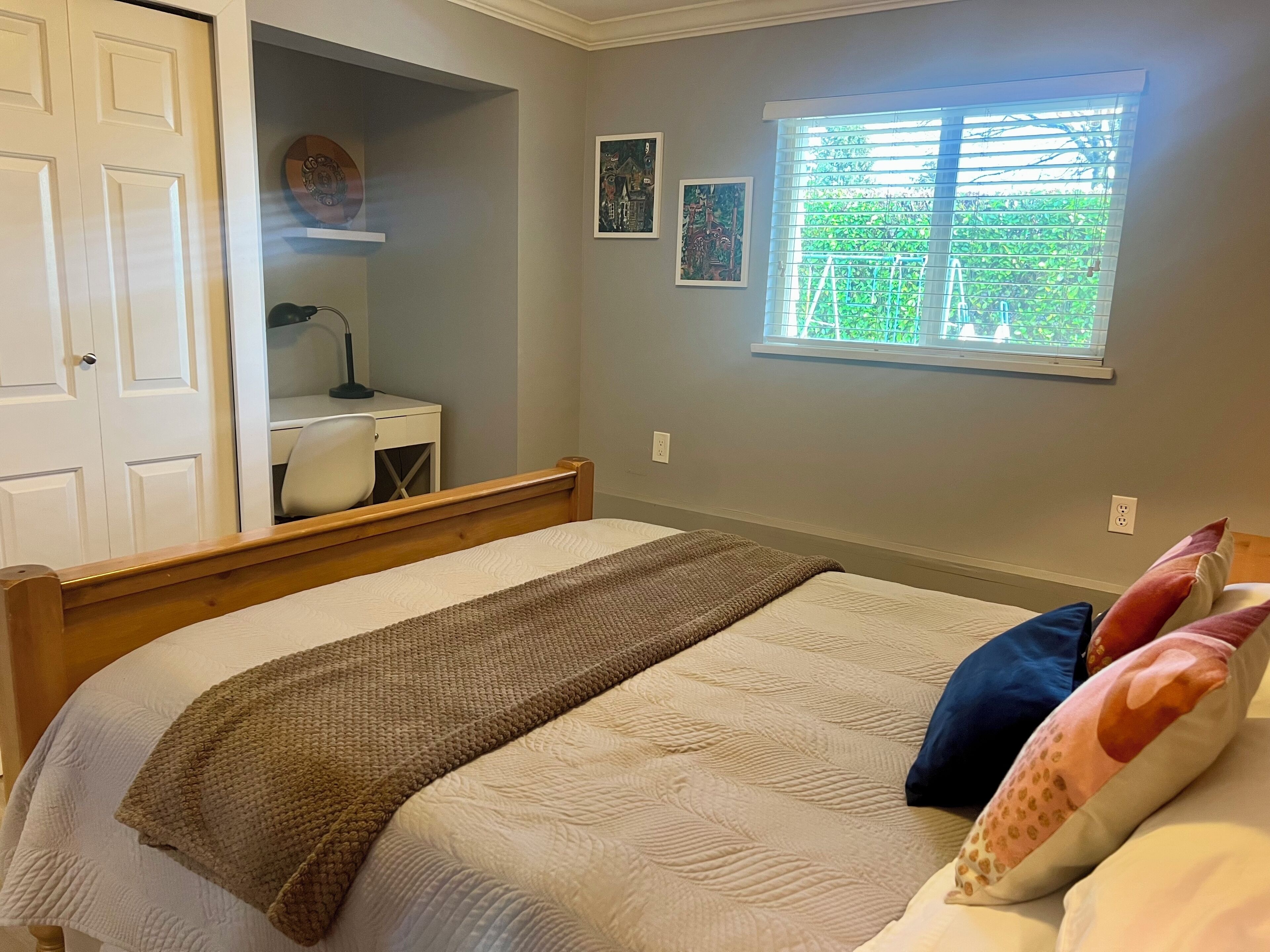 Un dormitorio con cama, escritorio y ventana.