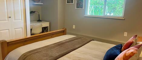 Un dormitorio con cama, escritorio y ventana.